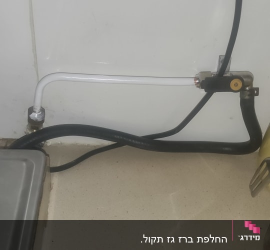 צינור גז לבן ושחור עם שסתום על קיר לבן